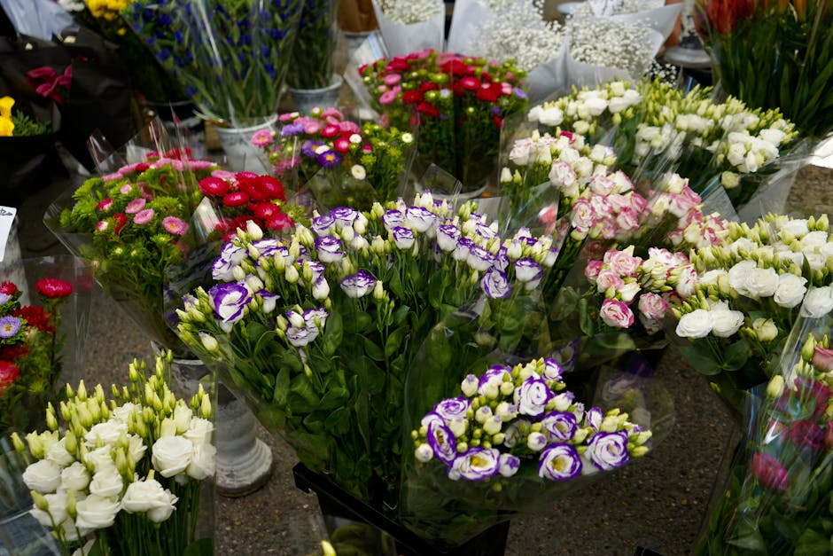 A colorful array of freshly cut flower bouquets displayed on a dark countertop at a flower stall, including purple and white lisianthus, pink and white roses, red and pink daisy-like flowers, and whit