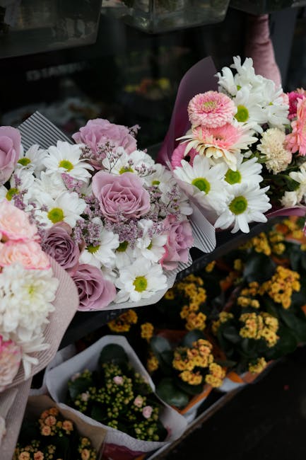 A display of fresh floral bouquets arranged for flower delivery in South Hornchurch, featuring pastel pink roses, white daisies with yellow centers, and pink chrysanthemums wrapped in light pink and p